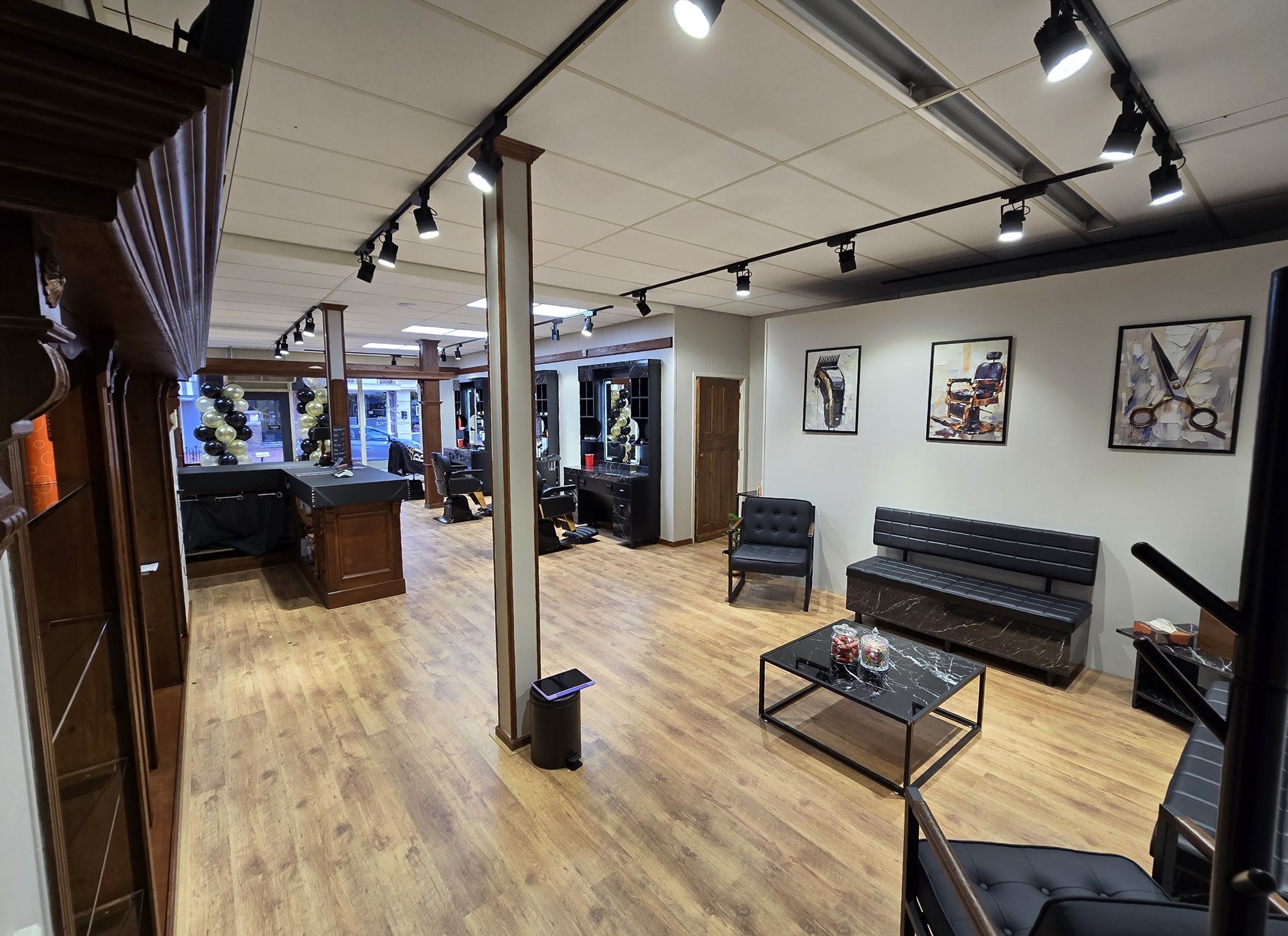 Interieur van The Gentlemen's Barber: houten zuilen, de werkplekken en de lounge met zwarte banken
