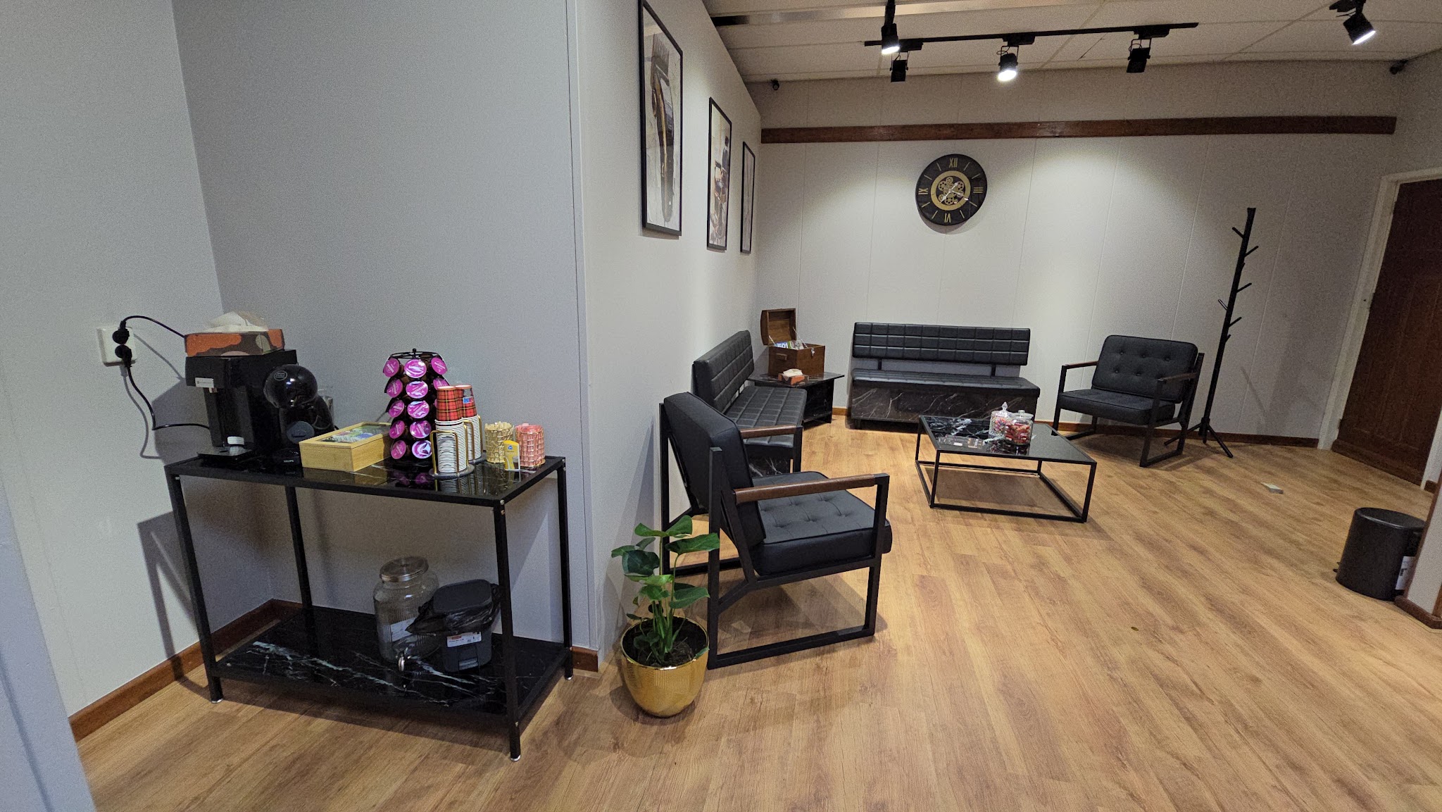 De lounge van de barbershop met een salontafel, zwarte stoelen en een tafel met verzorgingsproducten