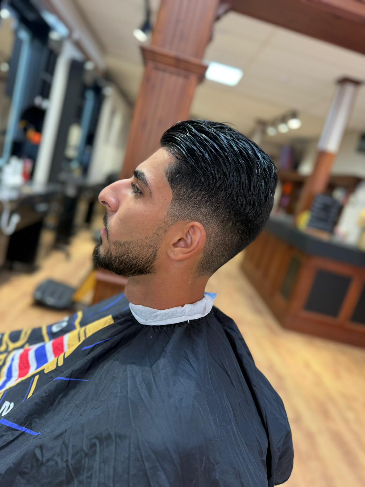 Klant in profiel met een strakke fade en een bijgewerkte baard, in de stoel bij The Gentlemen's Barber